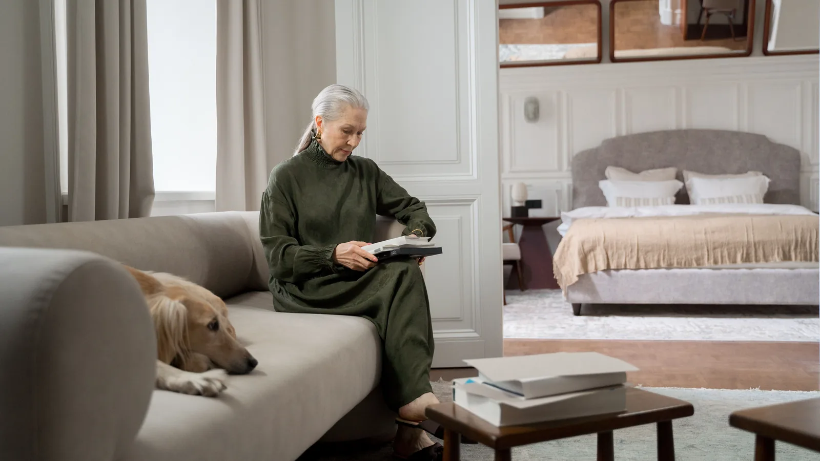 Femme senior lisant dans son salon, son chien allongé près d'elle