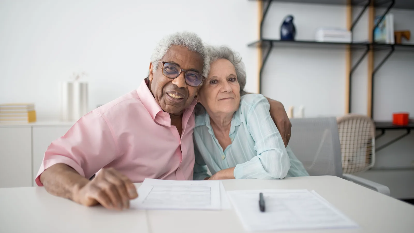 Couple de seniors souriants examinant des documents à leur table